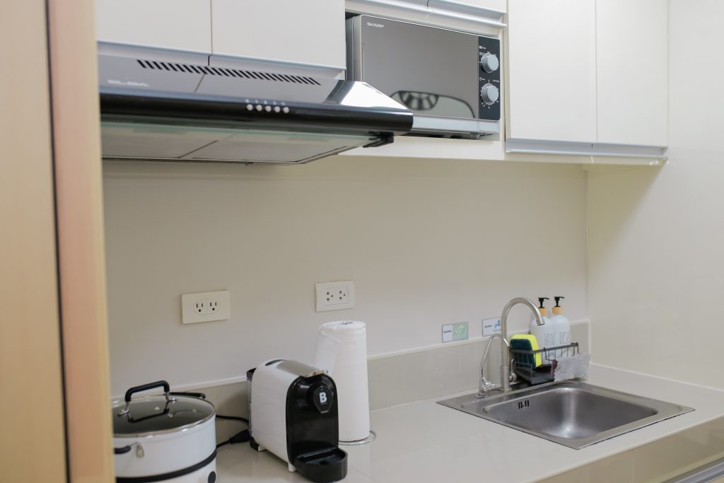 The kitchen area with induction cooker, coffee machine, rice cooker, kettle and microwave oven.