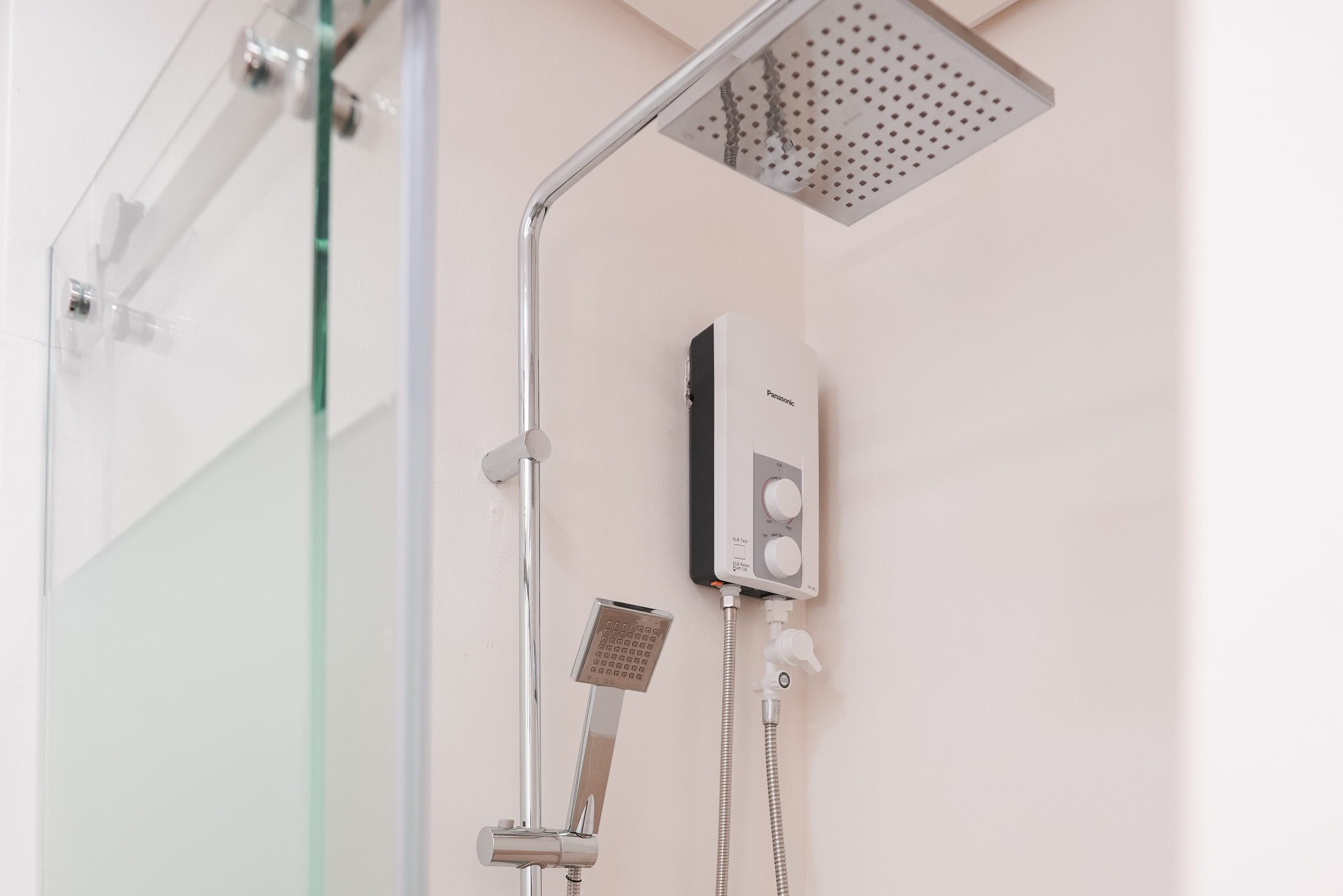 Modern and clean bathroom space with shower enclosure, shower and water heater.