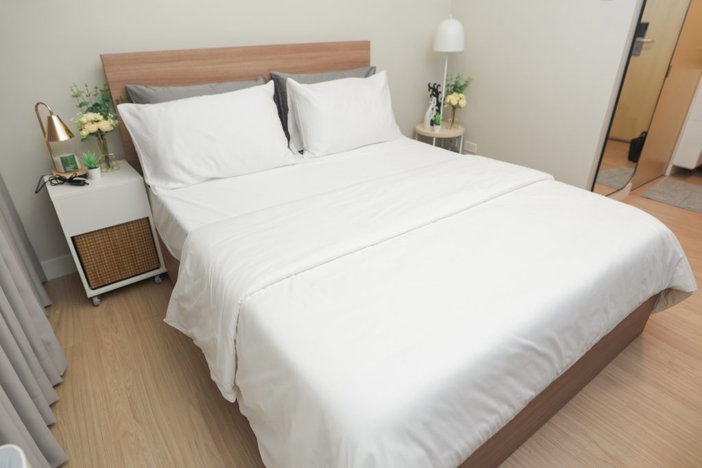 A queen size plush bed with white comforter and pillows.